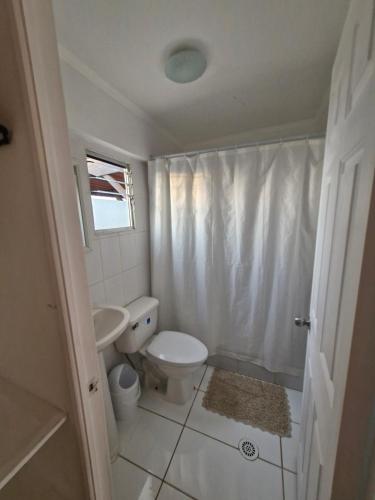La salle de bains blanche est pourvue de toilettes et d'un lavabo. dans l'établissement Hosteria Piedra Blanca, à Taltal