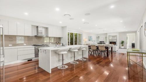 a kitchen with white cabinets and a wooden floor at The Clubhouse Pokolbin in Pokolbin