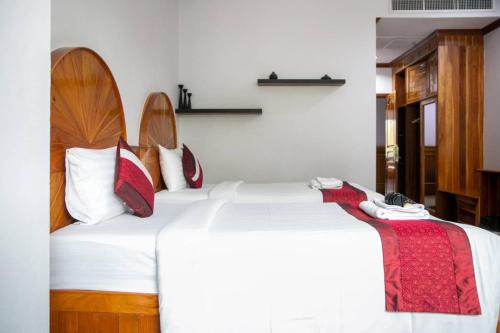 a bedroom with two beds with white sheets and red pillows at Sky View Hotel Buriram in Buriram