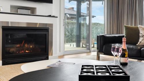 a living room with a fireplace and two wine glasses at Belleview Hunter in Pokolbin