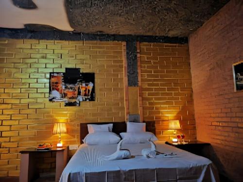 1 dormitorio con cama y pared de ladrillo en Hotel Vinchenso en Kaduwela