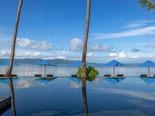 a pool of water with palm trees and umbrellas at Explorar Koh Phangan - Adults Only Resort and Spa in Haad Rin