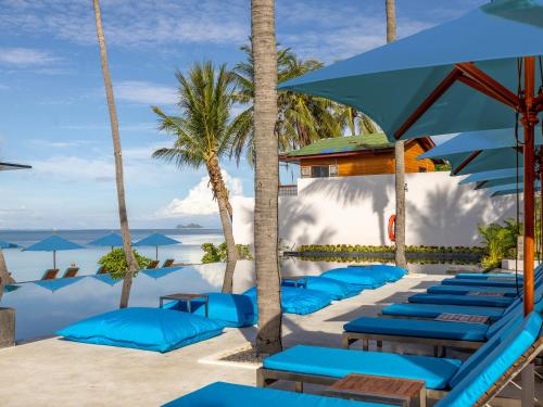 a pool with blue lounge chairs and umbrellas at Explorar Koh Phangan - Adults Only Resort and Spa in Haad Rin