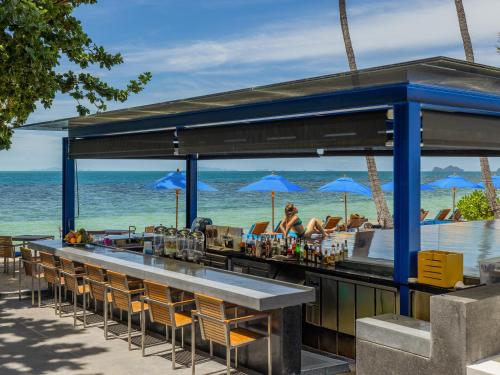 a bar at the beach with chairs and umbrellas at Explorar Koh Phangan - Adults Only Resort and Spa in Haad Rin