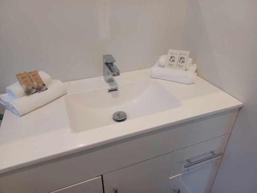 a white bathroom sink with two towels on it at Aqua Apartment in Napier