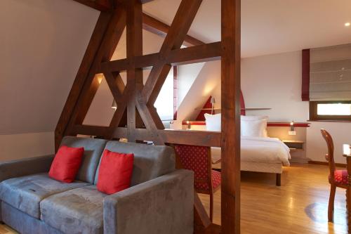 a bedroom with a bed and a couch with red pillows at Hotel Spa et Restaurant Au Chasseur in Birkenwald