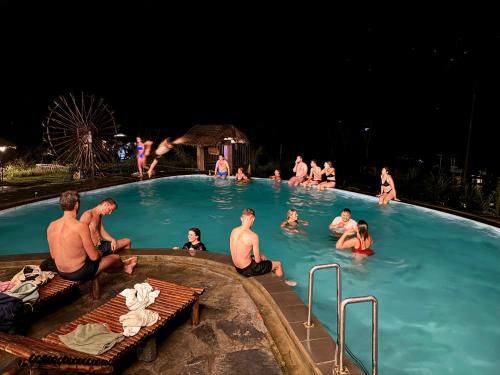 un groupe de personnes dans une piscine la nuit dans l'établissement Viet Hung Hostel - Motorbikes Rental- BUS TICKET, à Làng Lap