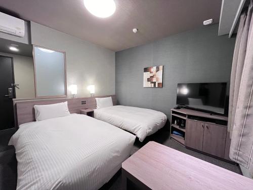 a hotel room with two beds and a flat screen tv at Hotel Route Inn Kuwana in Kuwana