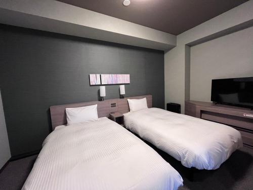 two beds sitting next to each other in a room at Hotel Route Inn Kuwana in Kuwana