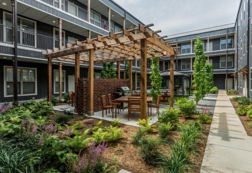 a garden with a wooden pergola in front of a building at Sleepover 1BD 1BA Little Rock Apartments in North Little Rock