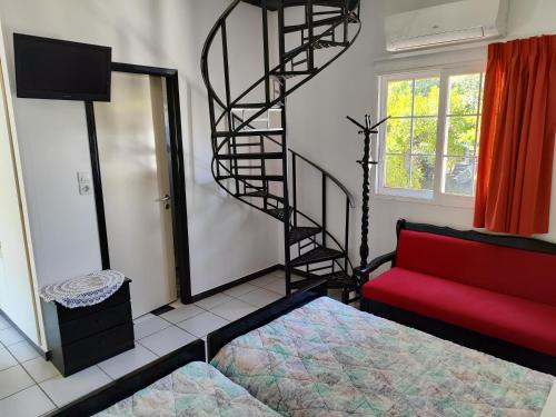 a living room with a red couch and a spiral staircase at CottonClub Villas in Tolo