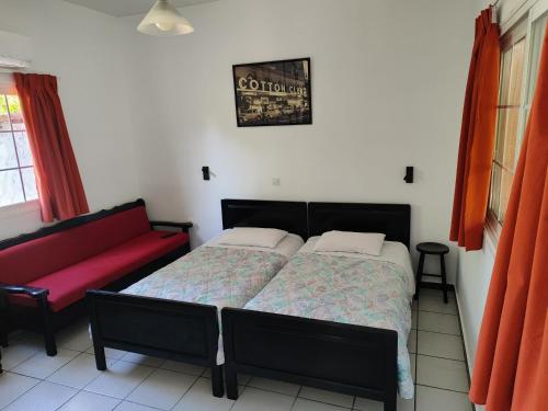 a bedroom with a bed and a red couch at CottonClub Villas in Tolo