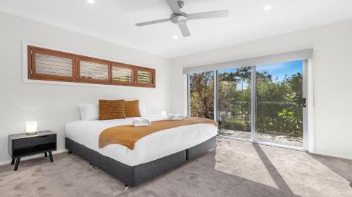 a bedroom with a bed and a large window at Alkira at The Vintage in Pokolbin
