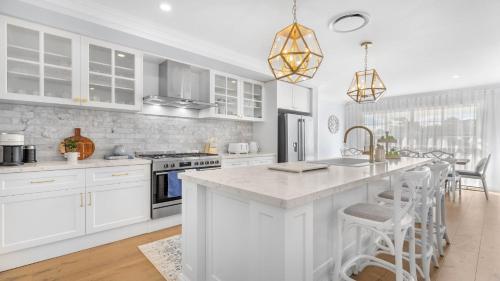 a kitchen with white cabinets and a kitchen island with bar stools at Montauk House in Pokolbin