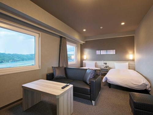 una camera d'albergo con letto, divano e tavolo di Hotel Route Inn Kuwana a Kuwana