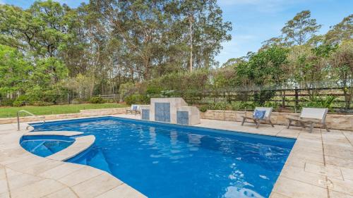 een zwembad met blauw water in een tuin bij Vintage Lodge in Pokolbin