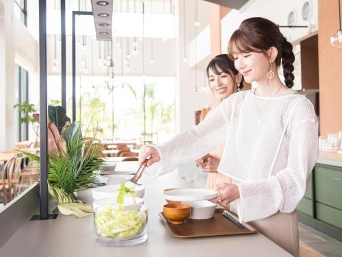 a woman preparing food in a kitchen at REF Okinawa Arena by VESSEL HOTELS in Okinawa City