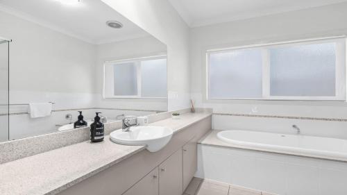 a white bathroom with a sink and a bath tub at Amaroo Lodge - The Vintage in Pokolbin