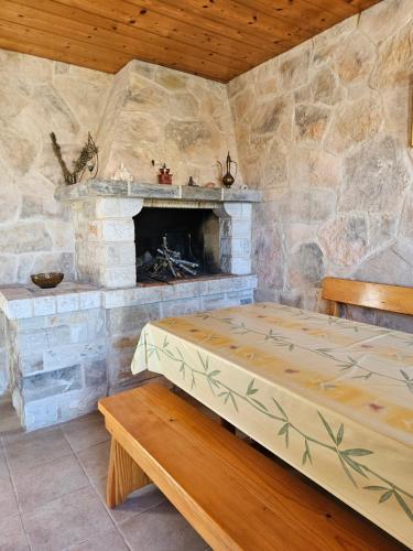 a room with a stone fireplace and a bed and a bench at Villa Kety in Prigradica