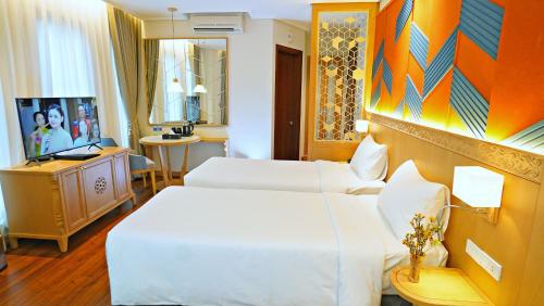 una camera d'albergo con due letti e una televisione di SAIGON_AROMA_HOTEL a Hanoi