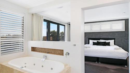 a white bathroom with a tub and a bed at Villa Saachi - The Vintage in Pokolbin