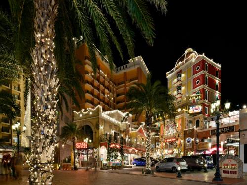 a city street with many buildings and palm trees at night at Lequ Okinawa Chatan Spa ＆ Resort in Chatan