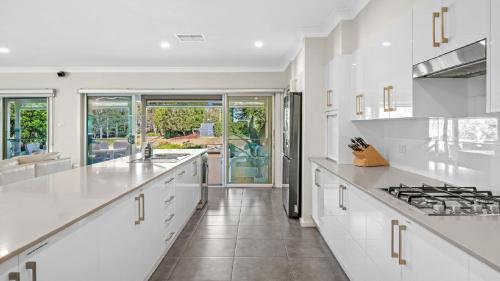 a white kitchen with white counters and a stove at Cypress Point Lodge - The Vintage in Pokolbin