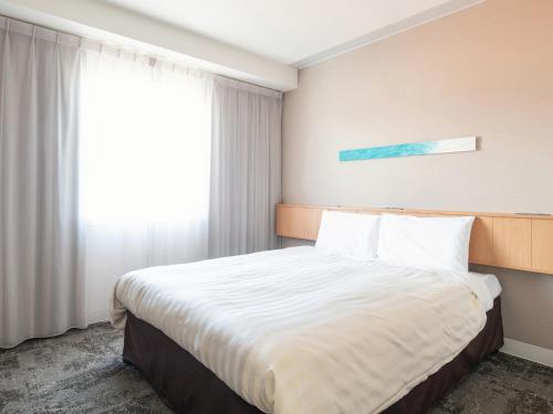 a bedroom with a large bed with a window at Vessel Hotel Ishigakijima in Ishigaki Island