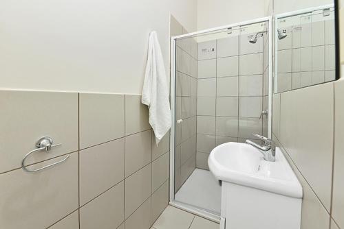 een witte badkamer met een douche en een wastafel bij 51CR3 - Lovely One Bedroom Apt Next to RMIT! AC, 50incTV in Melbourne