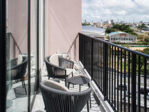 a balcony with chairs and a view of a city at REF Okinawa Arena by VESSEL HOTEL in Okinawa City