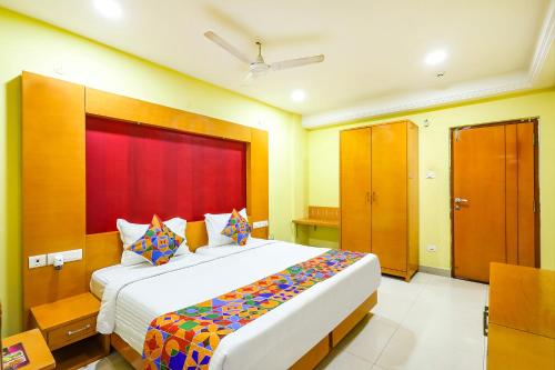 a bedroom with a large bed with a red headboard at FabHotel Prime Mahalaya Residency in Chennai