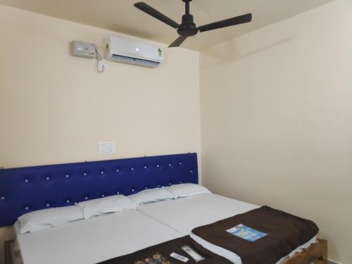 a bedroom with a bed with a blue headboard and a fan at Redkar Rooms Gokarna Beach front AC And Non AC Rooms in Gokarn
