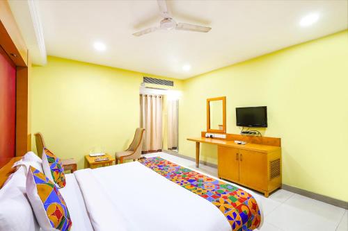 a bedroom with a bed and a desk and a television at FabHotel Prime Mahalaya Residency in Chennai