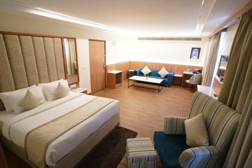 Cilantro Comfort Jaipur في جايبور: غرفه فندقيه بسرير واريكه