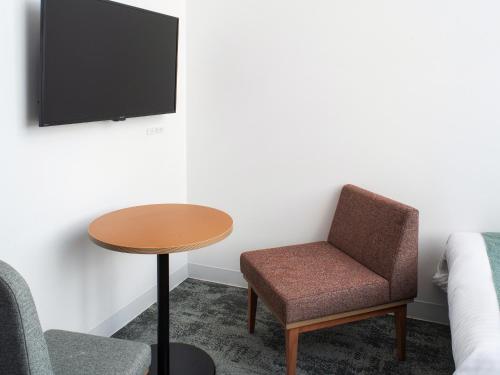 a room with a table and a chair and a tv at REF Okinawa Arena by VESSEL HOTELS in Okinawa City