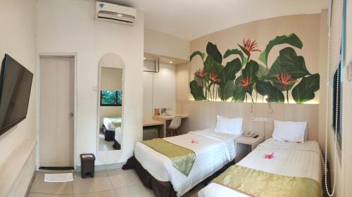 a hotel room with two beds and a painting on the wall at D'Bamboo Suites in Jakarta