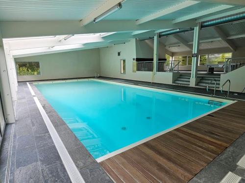 une grande piscine avec de l'eau bleue dans un immeuble dans l'établissement La Maison du Grand Sapin, à Saint-Gatien-des-Bois
