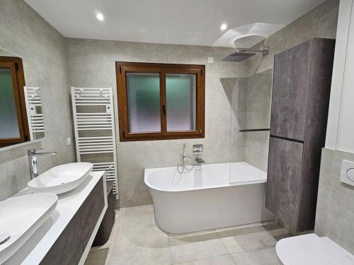 łazienka z 2 umywalkami, wanną i toaletą w obiekcie Belle maison dans domaine d'exception w mieście Saint Gatien des Bois