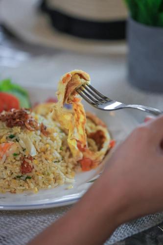 a person eating food on a plate with a fork at Navalia Villa Bedugul in Bedugul