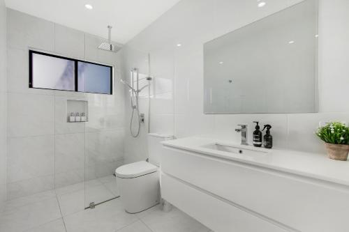 Elvis on Brodie - luxury boutique accommodation في كوفس هاربور: حمام ابيض مع مرحاض ومغسلة