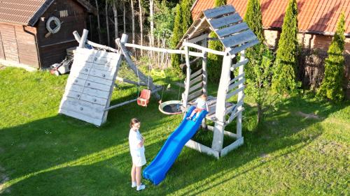 two children playing on a playground in a yard at Bajkowe Domki Marzeń Taborecik in Węgorzewo