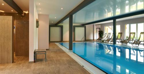 a large swimming pool with chairs in a building at Hotel Spa et Restaurant Au Chasseur in Birkenwald