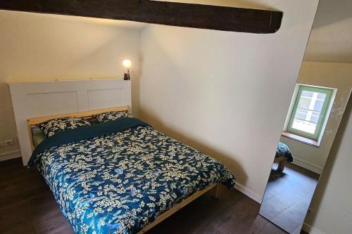 a bedroom with a bed with a blue and white comforter at Le Petit Grenette in Charlieu