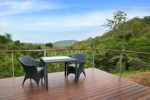 a table and chairs on a deck with a view at Crystal Creek Rainforest Retreat in Crystal Creek