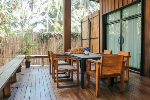 a patio with a table and chairs on a deck at บ้านไร่มีสุข Baanrai Meesuk in Surat Thani