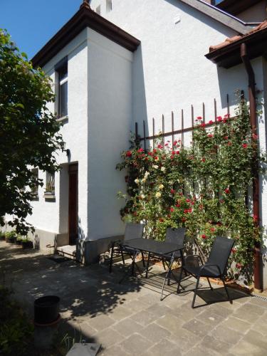 a table and chairs in front of a house with flowers at Talblick in Oberroßla