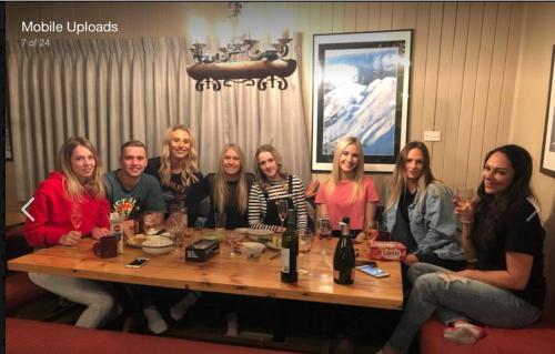 un grupo de personas sentadas alrededor de una mesa de madera en Nutcracker Ski Club en Mount Buller