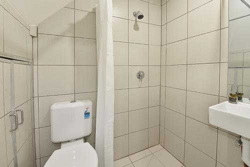 La salle de bains blanche est pourvue de toilettes et d'un lavabo. dans l'établissement Lovely One Bedroom Apt Next to RMIT! AC, 50inc TV, à Melbourne