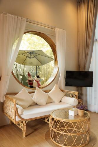 a living room with a couch and a round mirror at บ้านไร่มีสุข Baanrai Meesuk in Surat Thani