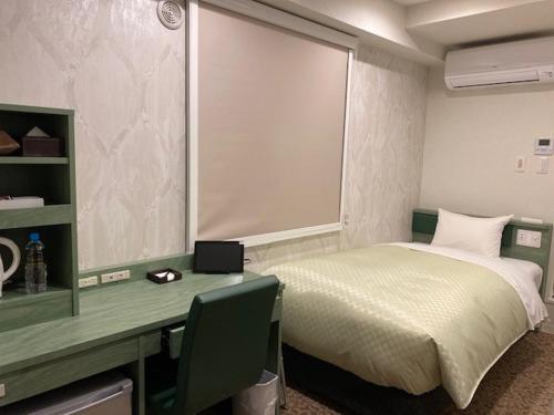 a bedroom with a bed and a desk with a computer at Hotel Front Inn Fukuoka Airport in Fukuoka